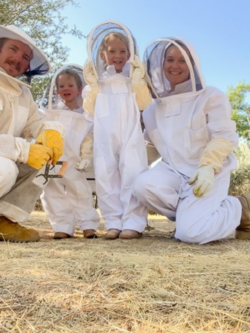 family of 4 in bee keeper suits smiling together