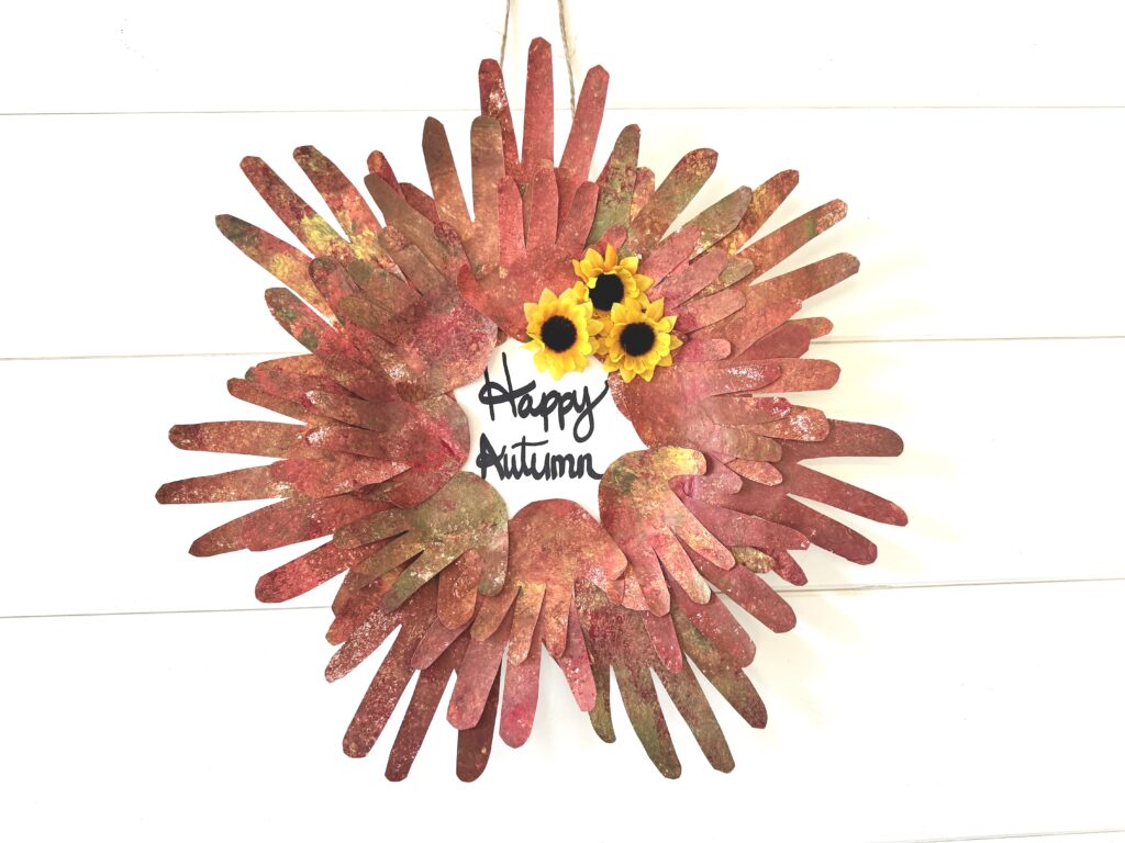 painted paper handprint fall kid craft hanging on a shiplap wall